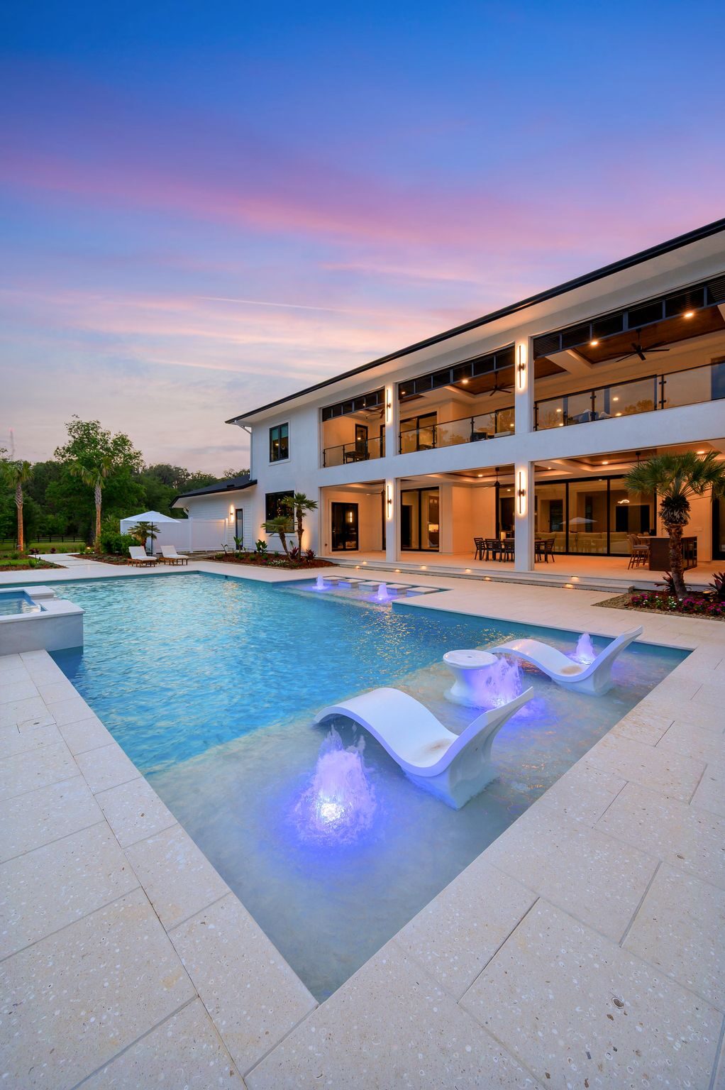 Custom pool at dusk with in-water lounge chairs and bubbler fountains